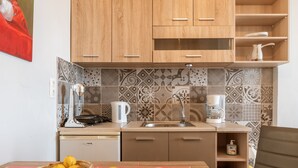 Een keuken met houten kastjes, een betegelde achterwand, een koffiezetapparaat en een schaal met citroenen op het aanrecht.