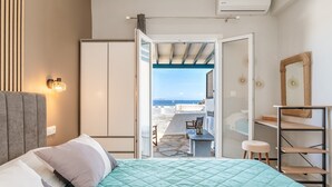 A bedroom with a bed, a wardrobe, a desk, a chair, and a view of the sea. - Holiday Home 'Porto Galini Tinos Myrsini 106' with Private Terrace, Wi-Fi and Air Conditioning (LAOUTI)