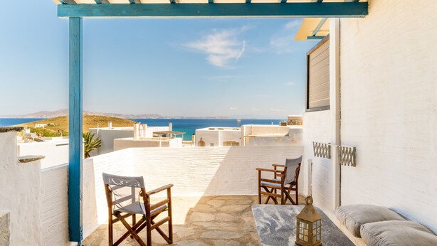 A terrace with a view of the sea, stone flooring, and two wooden chairs. - Holiday Home 'Porto Galini Tinos Myrsini 106' with Private Terrace, Wi-Fi and Air Conditioning (LAOUTI)