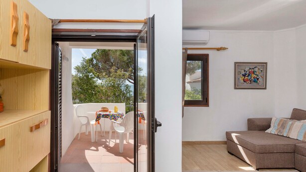 Una habitación con puerta corrediza de vidrio que da a un patio exterior con mesa y sillas, un sofá y un cuadro en la pared.