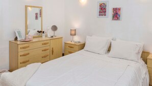 Un dormitorio con cama, cómoda, mesita de noche, lámpara y decoración en la pared.