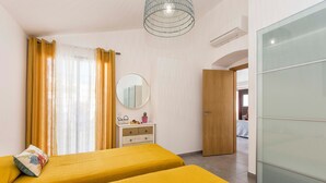 Une chambre avec deux lits, une commode, un miroir, une porte et une vue sur une autre pièce.