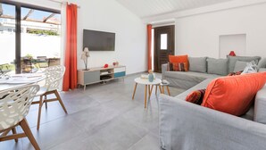 Un salon moderne avec un canapé, un téléviseur et un coin repas.