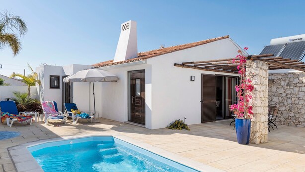 Un espace aménagé au bord de la piscine, comprenant une piscine, des chaises longues et un coin salon abrité.