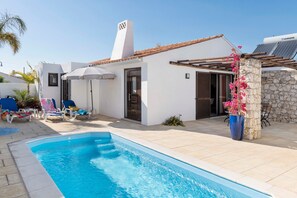A poolside area with a swimming pool, lounge chairs, and a covered seating area. - Villa 'Petala' with Private Pool, Wi-Fi and Air Conditioning (Albufeira)