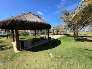 A grassy area with thatched-roof structures and palm trees. - GranSol, Terreo, Pé na areia, 03 qtos, Até 10 hóspedes, vizinho ao B.PARK (Aquiraz)