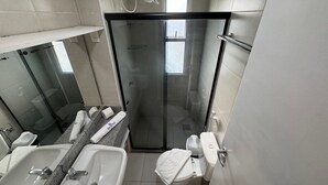 A modern bathroom with a glass shower enclosure, a sink with a granite countertop, and a toilet with a towel on top. - GranSol, Terreo, Pé na areia, 03 qtos, 08 hóspedes, a 600m do B PARK (Aquiraz)