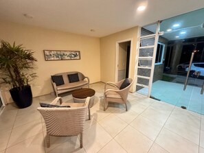 Sala de estar com sofá, duas poltronas, mesa de centro e planta em vaso.