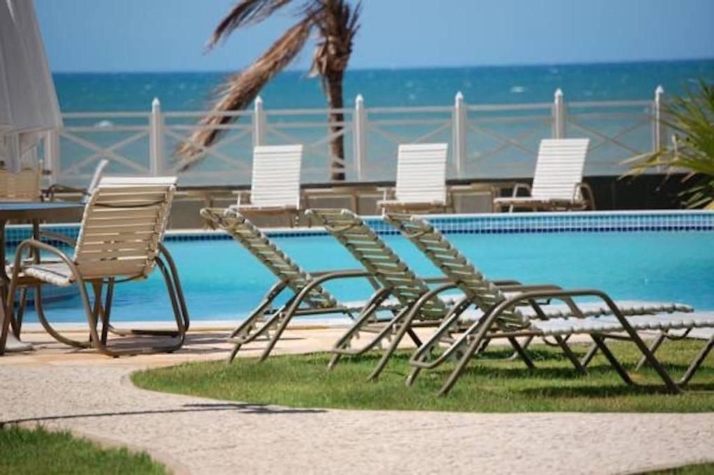 A poolside area with lounge chairs and a view of the ocean.