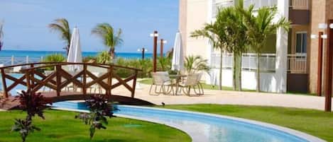 A hotel with a swimming pool, outdoor seating, and a view of the ocean.