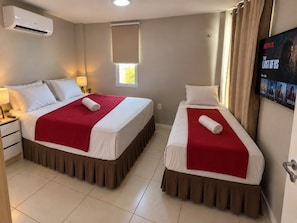 A hotel room with two beds, a TV, and an air conditioning unit. - GranSol, Terreo, Pé na areia, 03 qtos, Até 10 hóspedes, vizinho ao B.PARK (Aquiraz)