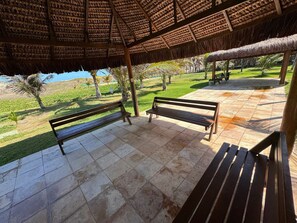 A covered outdoor seating area with benches and a view of a grassy landscape. - GranSol, Terreo, Pé na areia, 03 qtos, Até 10 hóspedes, vizinho ao B.PARK (Aquiraz)