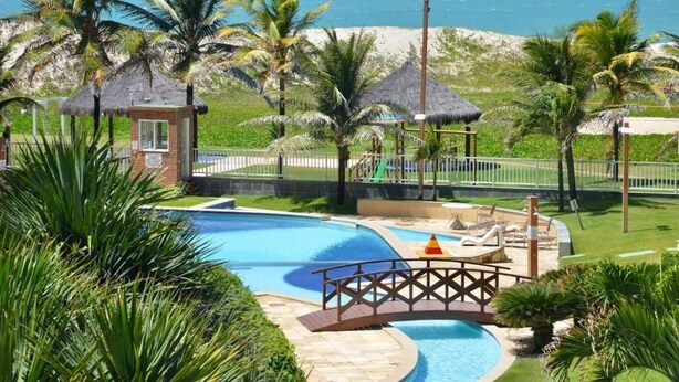 A pool area with a bridge, palm trees, and a beach view. - GranSol, Terreo, Pé na areia, 03 qtos, 08 hóspedes, a 600m do B PARK (Aquiraz)