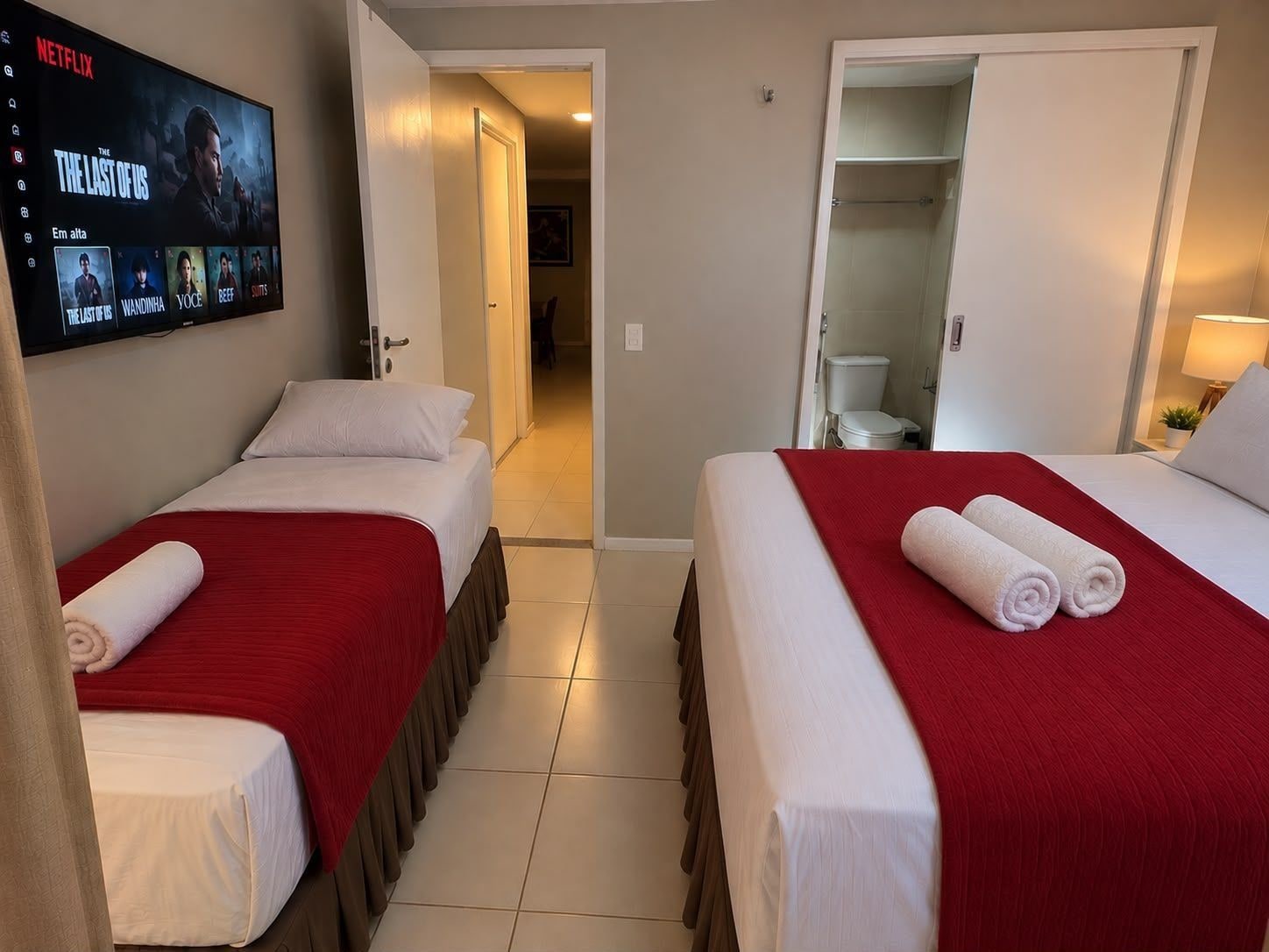 Ett hotellrum med två sängar, en tv som visar serien ”The Last of Us”, och ett badrum som syns genom en öppen dörr.