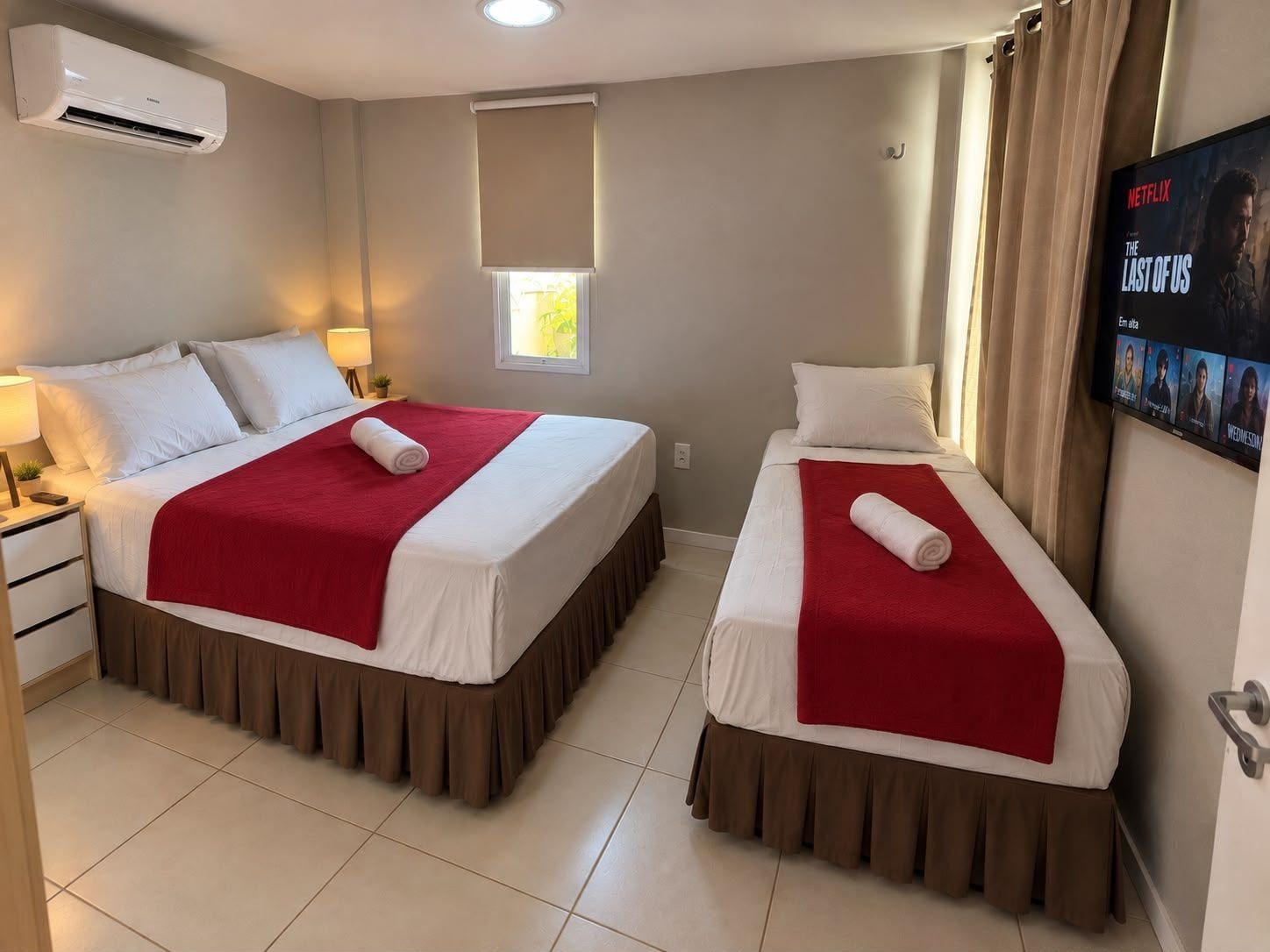 Habitació d'hotel amb dos llits, una televisió i un aire condicionat.