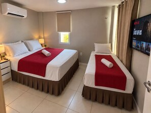 Habitación de hotel con dos camas, televisión y aire acondicionado.