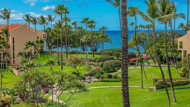 A resort with multiple buildings, palm trees, and a view of the ocean. - Kamaole Sands Two Bedrooms by Coldwell Banker Island Vacations (Kihei)