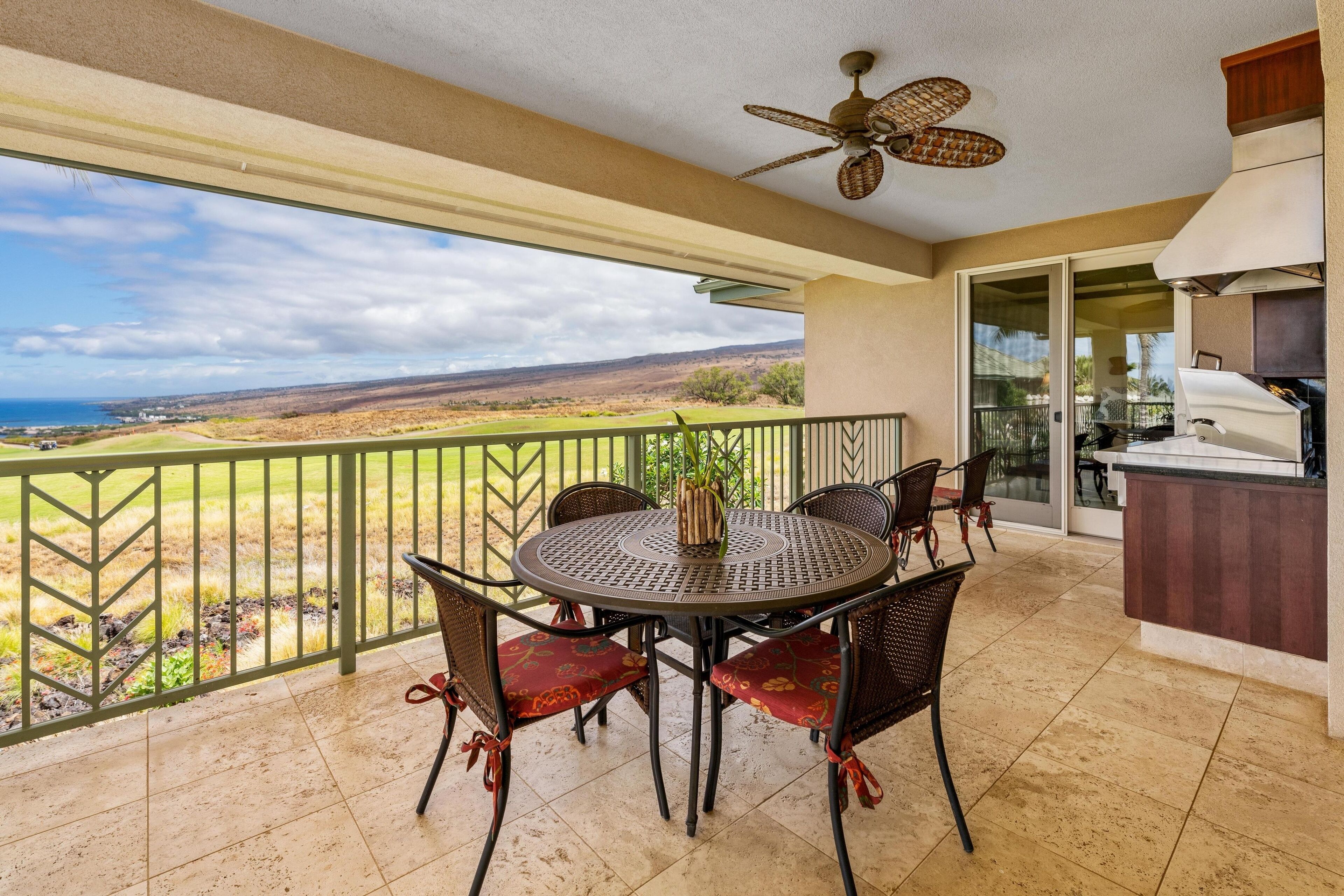 A balcony with a round table and chairs, a ceiling fan, and a view of the landscape.