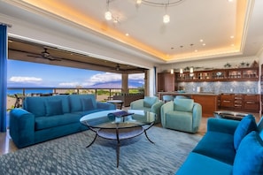 A spacious living area with a large sofa, a glass coffee table, and a view of the ocean. - Ho'olei Ocean View by Coldwell Banker Island Vacations (Kihei)