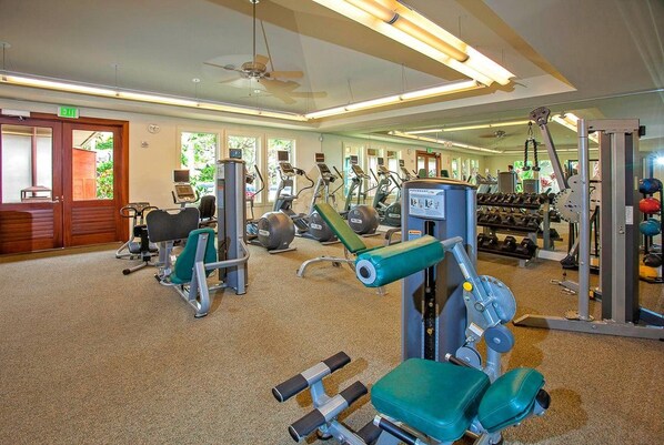 Un gimnasio con máquinas de cardio, bancos de pesas y pesas libres.