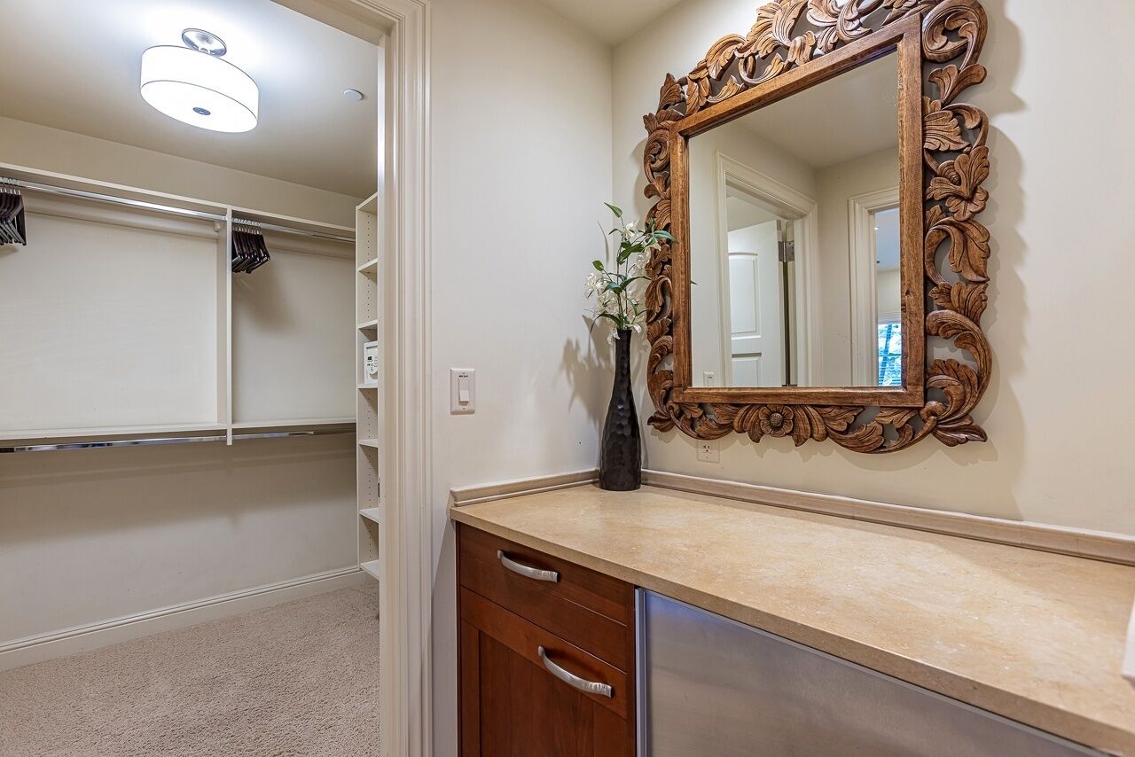 A bathroom with a vanity, a mirror with an ornate frame, and a vase with flowers.