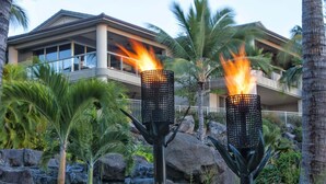 Ein modernes Hotel mit Poolbereich, ausgestattet mit zwei beleuchteten Fackeln und einem Wasserfall.