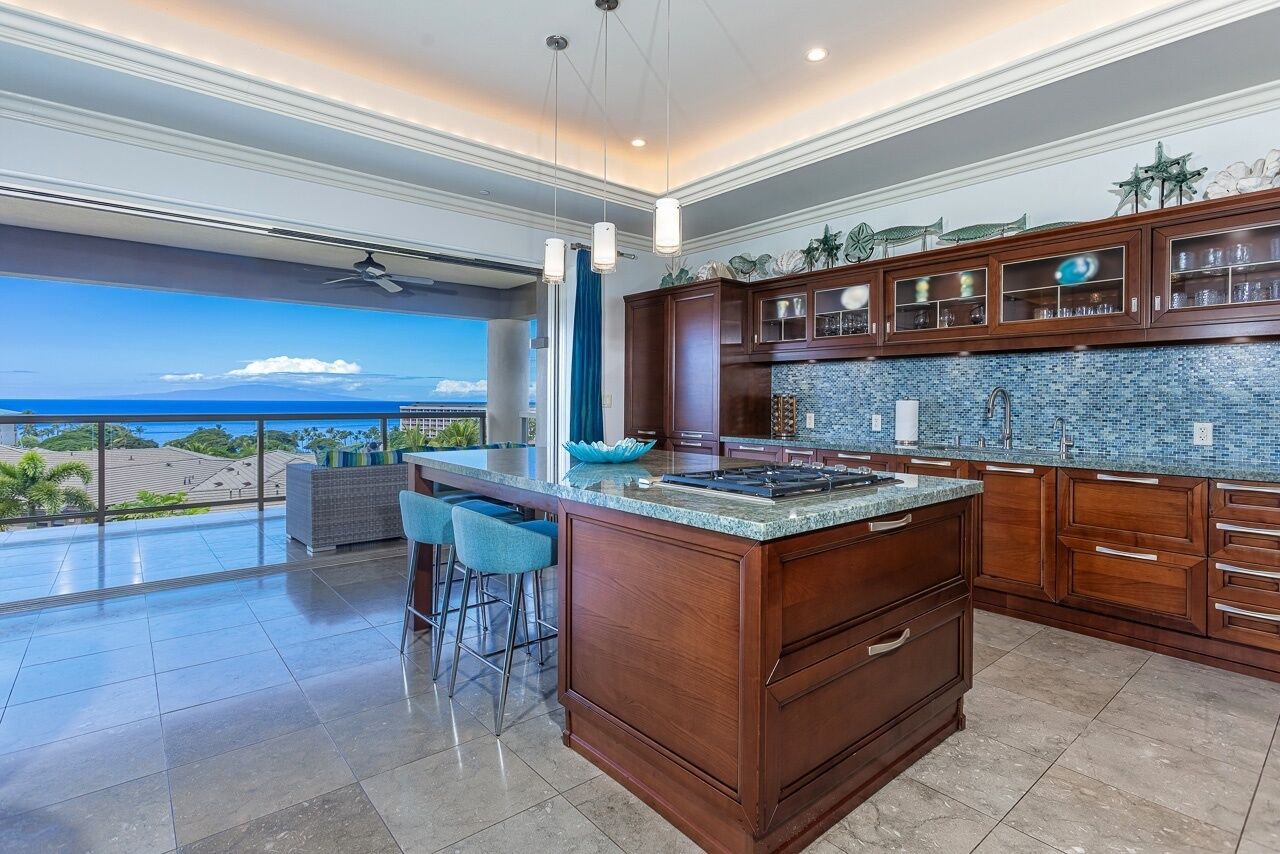 A spacious kitchen with a large island, wooden cabinets, and a view of the ocean.