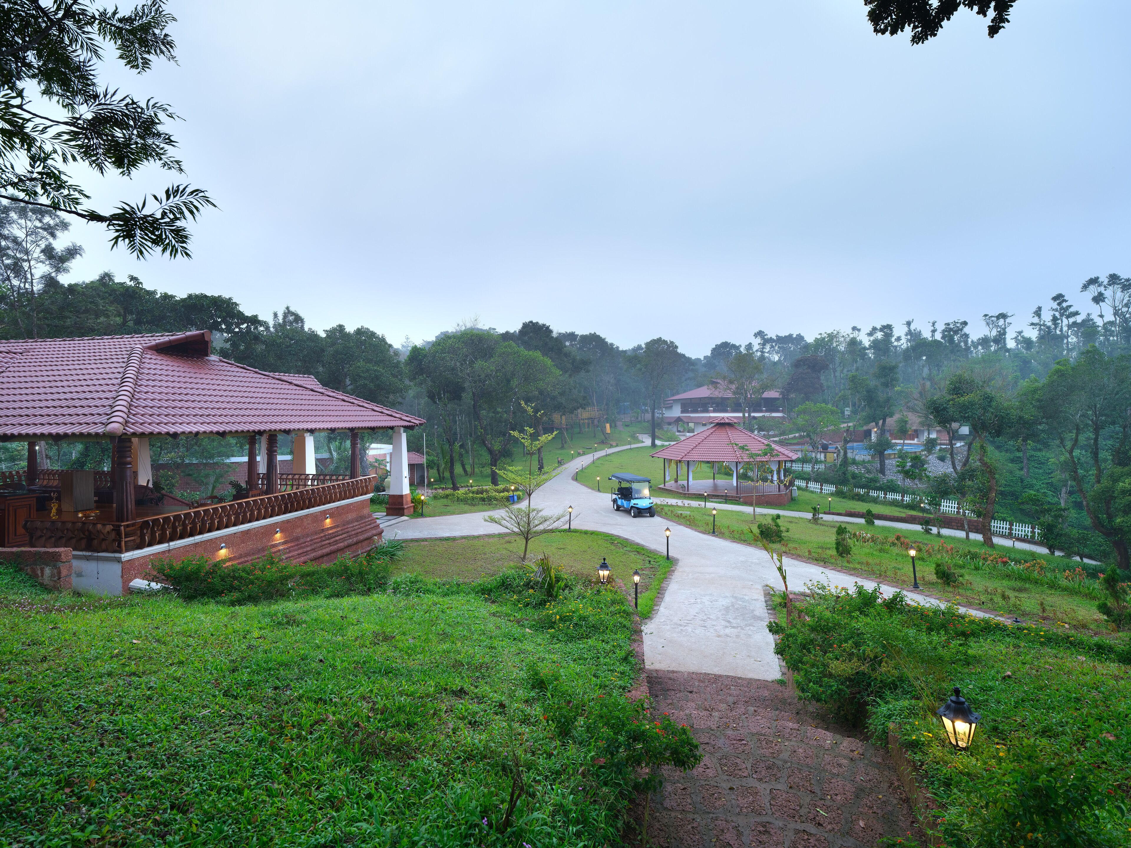A gazebo with a tiled roof, a pathway, and lush greenery.