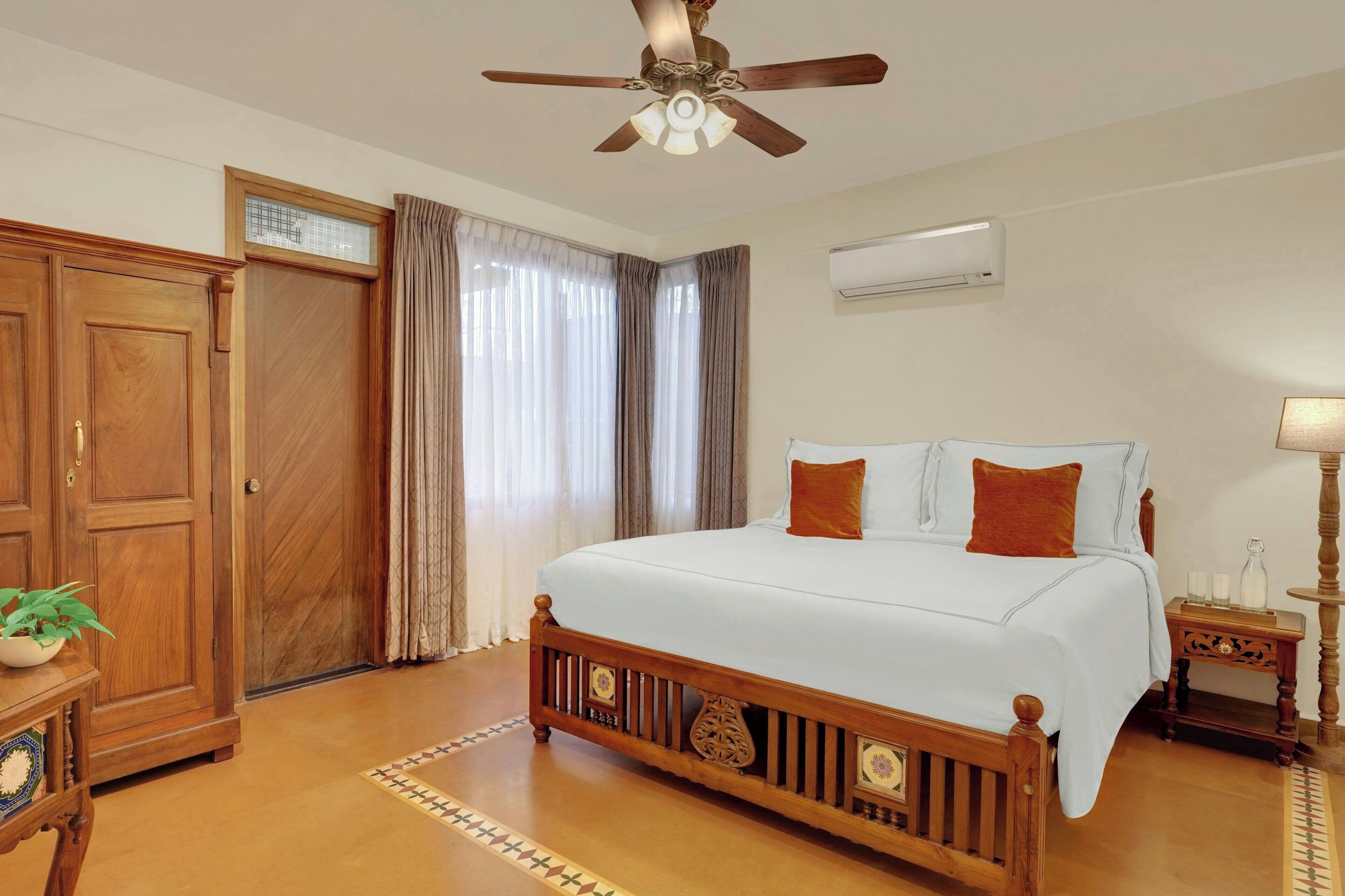 A bedroom with a wooden bed, a ceiling fan, a nightstand, and a window with curtains.