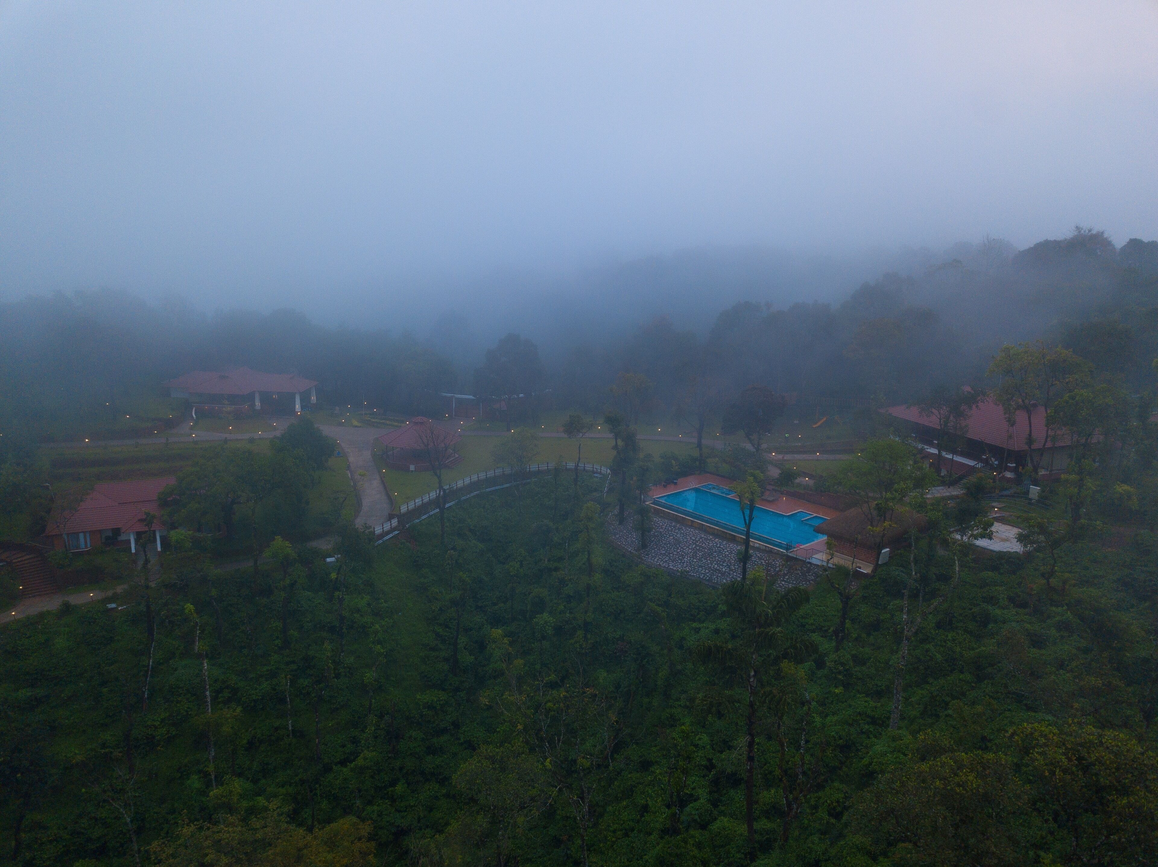 A view of a residential area with houses, a swimming pool, and a forested landscape.