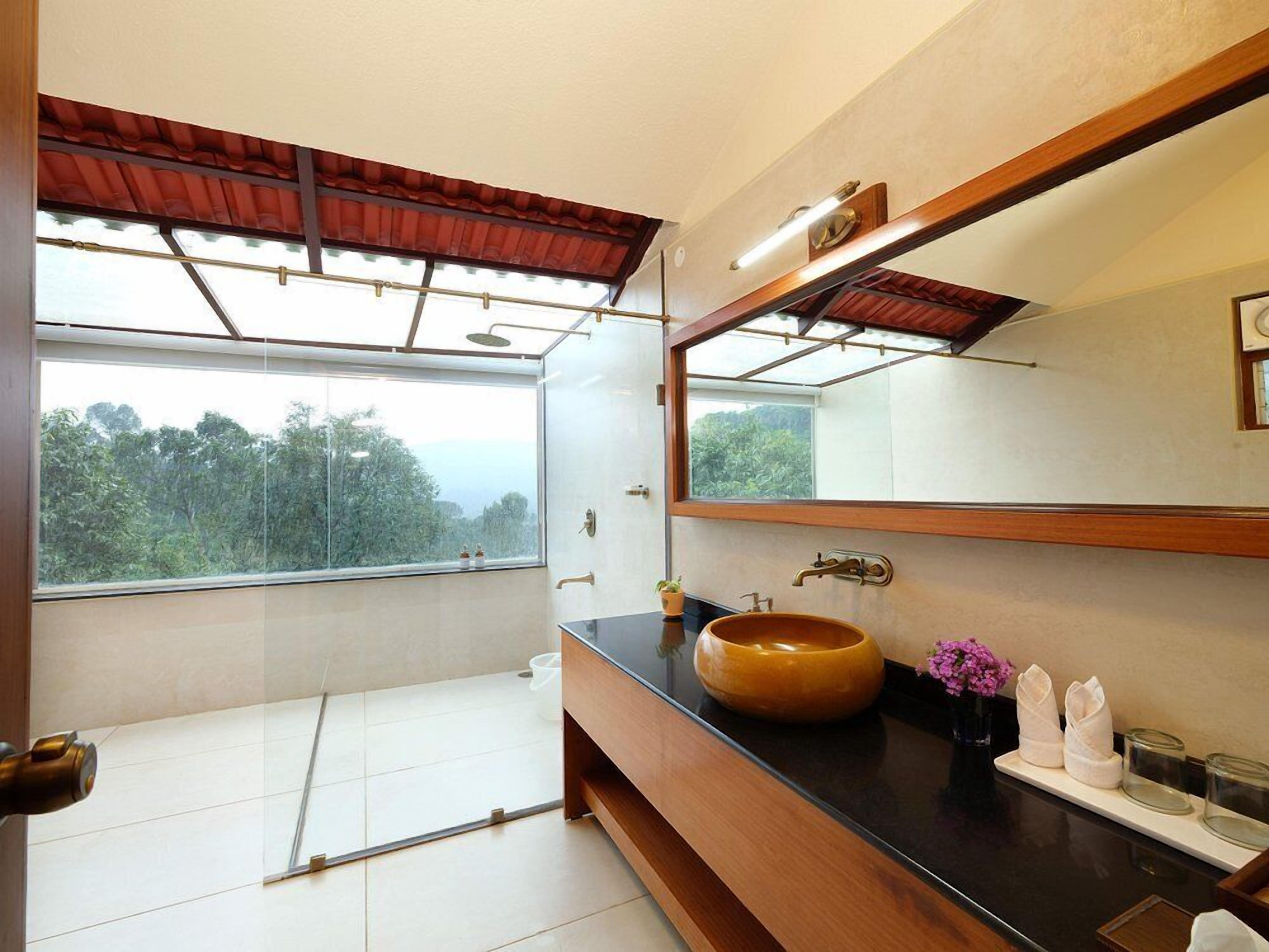 A modern bathroom with a large window, a wooden vanity, a round sink, and a mirror.