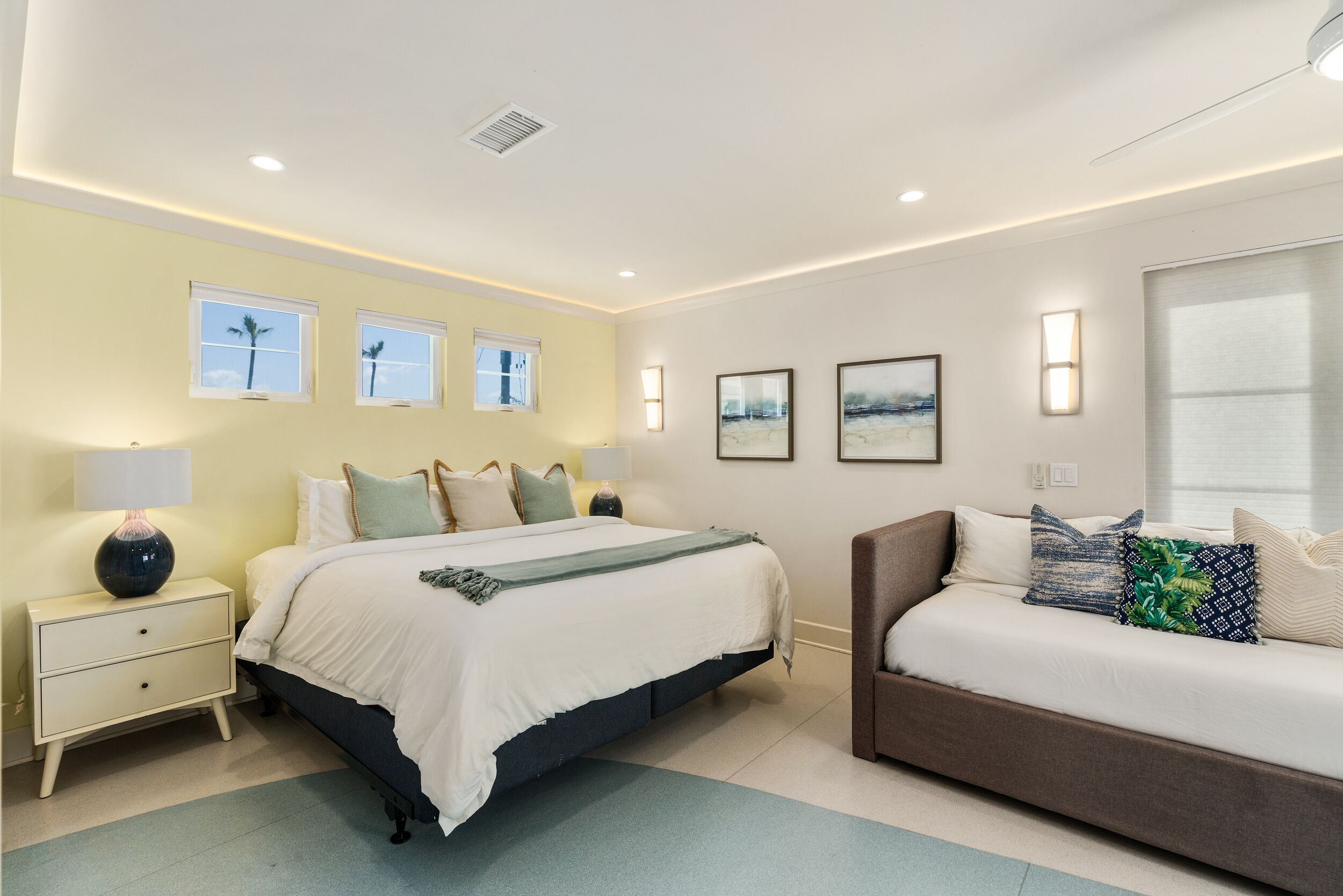 A bedroom with a bed, bedside tables, a sofa, and artwork on the walls.