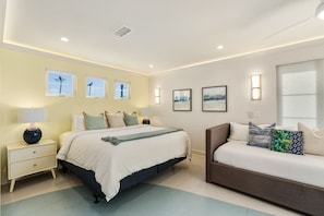 A bedroom with a bed, bedside tables, a sofa, and artwork on the walls.