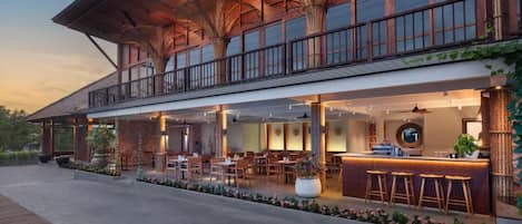 A modern hotel with a spacious outdoor seating area, a bar, and a covered patio with wicker furniture.