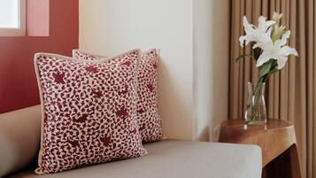Un sofá con cojines estampados y un jarrón con flores blancas sobre una mesita de madera.