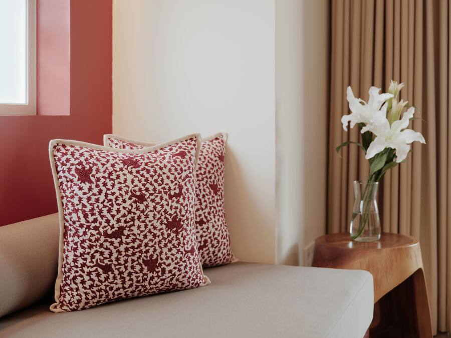 Un sofá con cojines estampados y un jarrón con flores blancas sobre una mesita de madera.