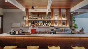 A bar area with a wooden ceiling, bar stools, and shelves with glasses and bottles. - Chesa Canggu (Canggu)