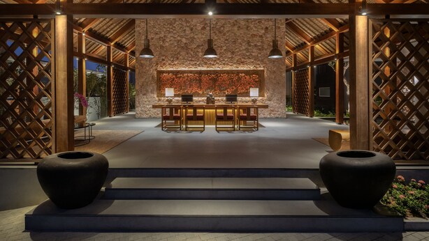 A reception area with a stone wall, wooden beams, and a desk with two chairs. - Chesa Canggu (Canggu)