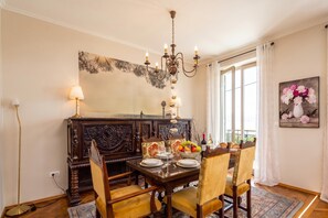 A dining area with a wooden table set for four, surrounded by upholstered chairs. A chandelier hangs above, and a large painting adorns the wall. - Rustic Villa Okra With Pool (Opatija)