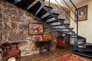 A room with a stone wall, a wooden bench, a red upholstered chair, a vintage sewing machine, and a black spiral staircase. - Rustic Villa Okra With Pool (Opatija)