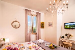 A bedroom with a bed, a window with curtains, a chandelier, a television, a desk with a chair, and a mirror. - Rustic Villa Okra With Pool (Opatija)