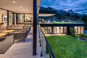 A modern house with a spacious living area, a balcony with a view of the garden, and a well-lit interior.