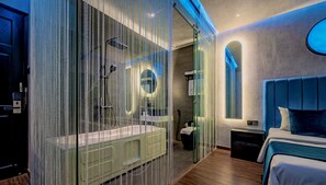 A modern bathroom with a glass shower enclosure, a round mirror, and a built-in sink.