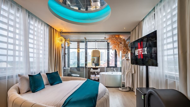 A modern hotel room with a large bed, a TV, and a view of the city. - Midas Hotel (Ho Chi Minh City)
