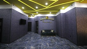 Um corredor com chão de mármore escuro, um sofá e parede com quadros e o texto "Krestel".