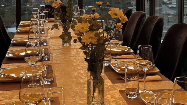 Mesa de jantar posta para refeição com vista para a cidade ao pôr do sol.