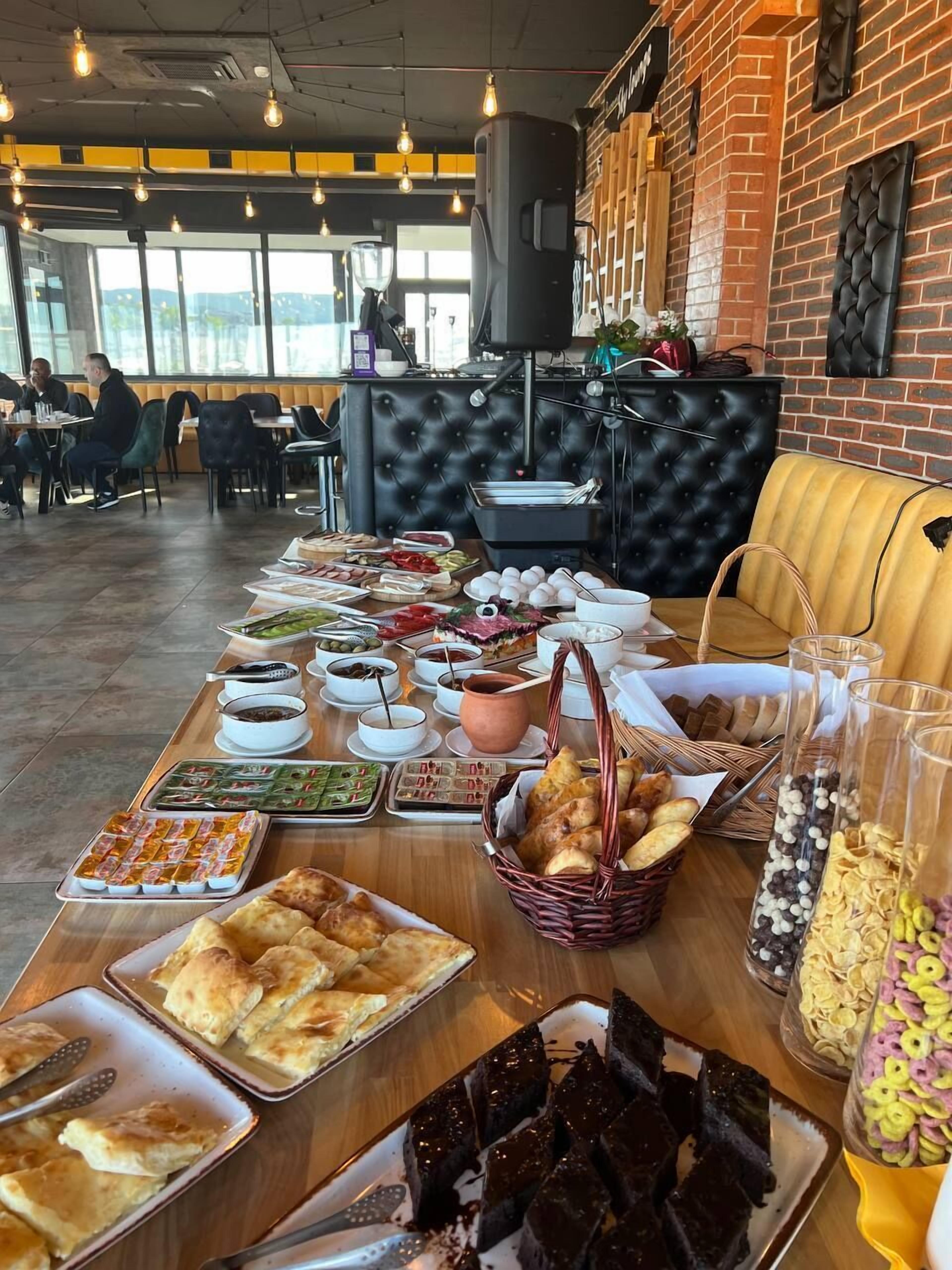 A buffet table with various food items and a seating area with a black cushioned bench and a yellow sofa.