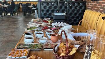 A buffet table with various food items and a seating area with a black cushioned bench and a yellow sofa.