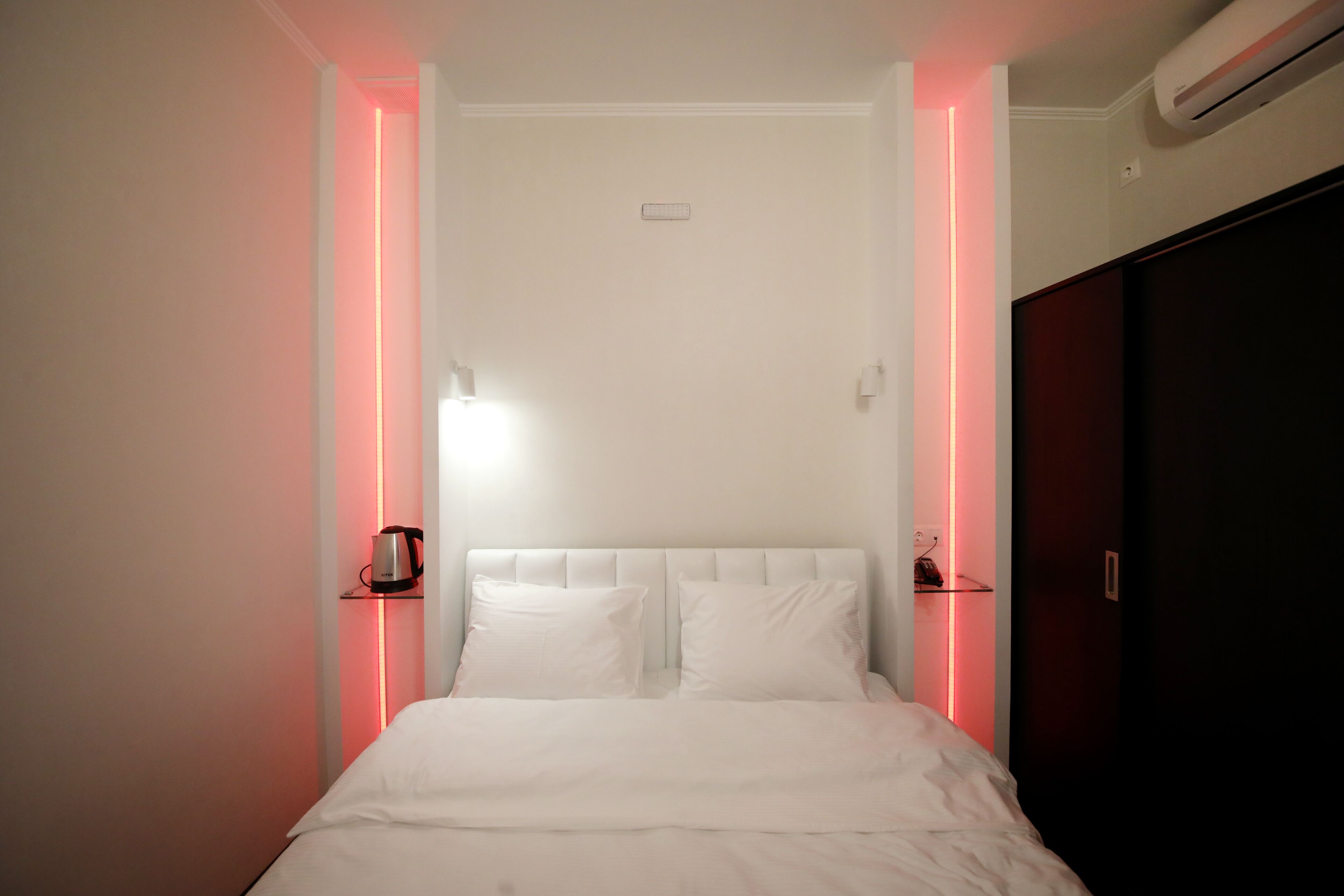 A neatly made bed with white linens, a headboard, and two bedside tables with lamps.
