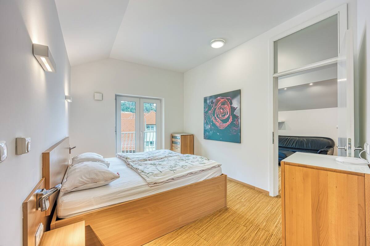 Une chambre moderne avec un lit en bois, un bureau et une grande fenêtre.